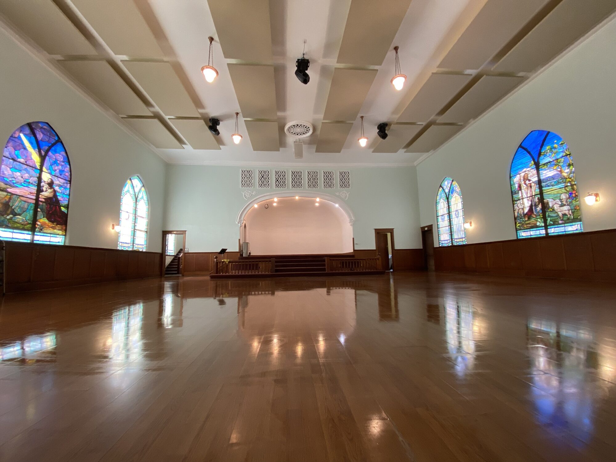 Open main room showing the polished wood floor and stained-glass windows