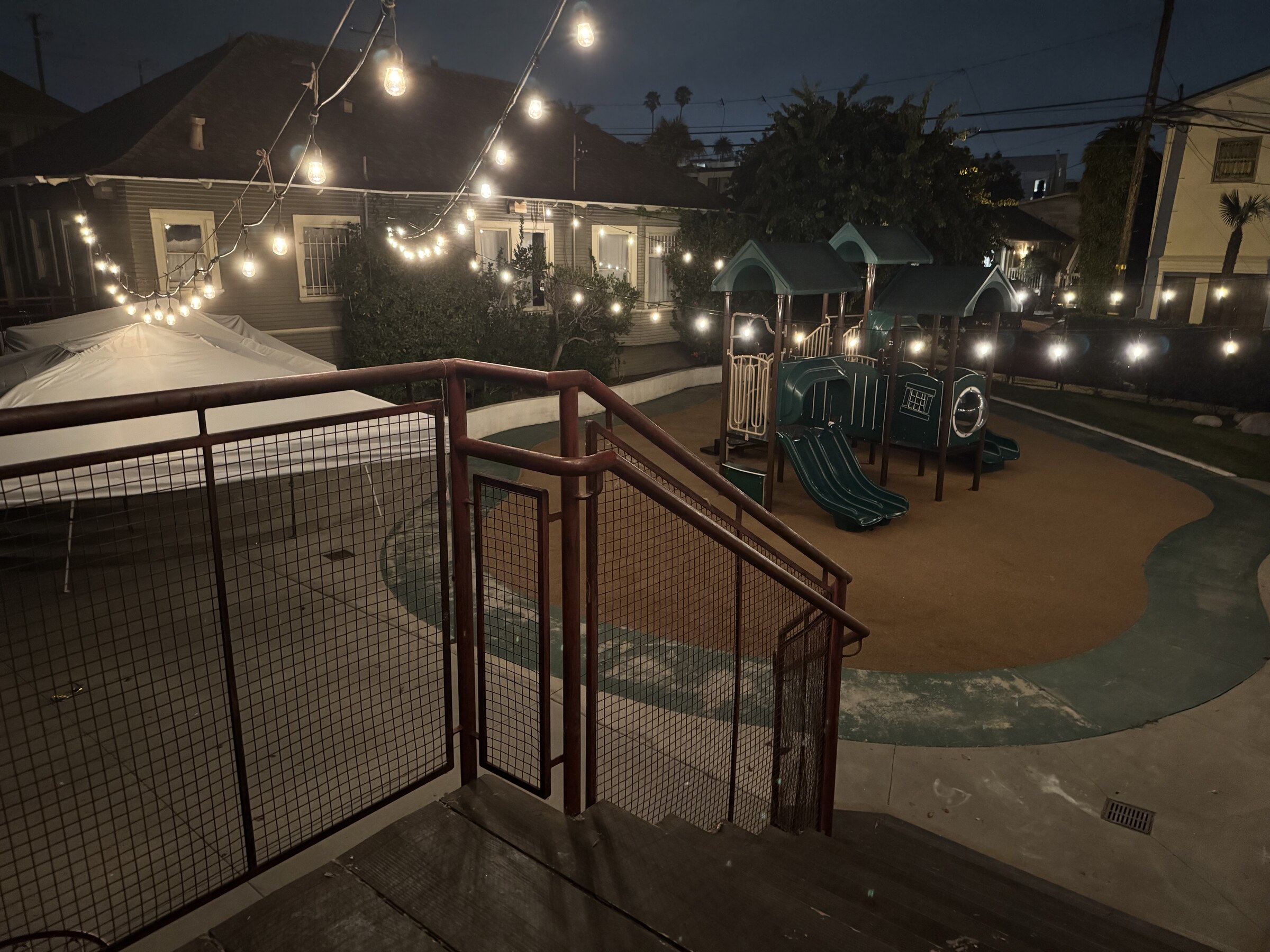Private yard with overhead lights and open gathering space at dusk